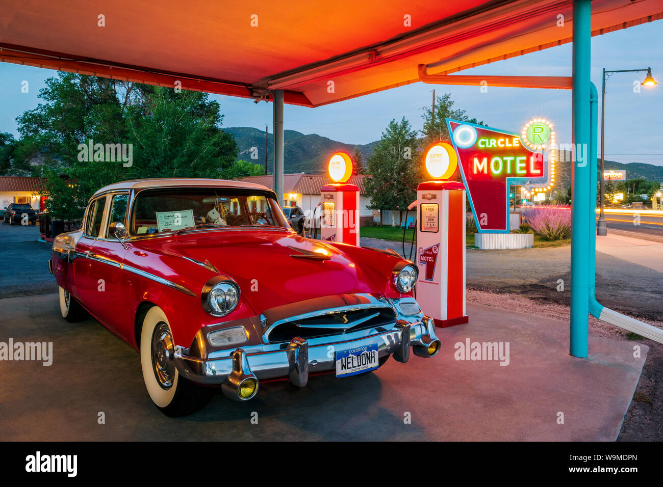 Dämmerung Blick auf 1955 Studebaker President classic car Vor antiken gas Pumpen elektrische Auto Ladegeräte konvertiert geparkt; den Kreis R Motel; Salida Stockfoto