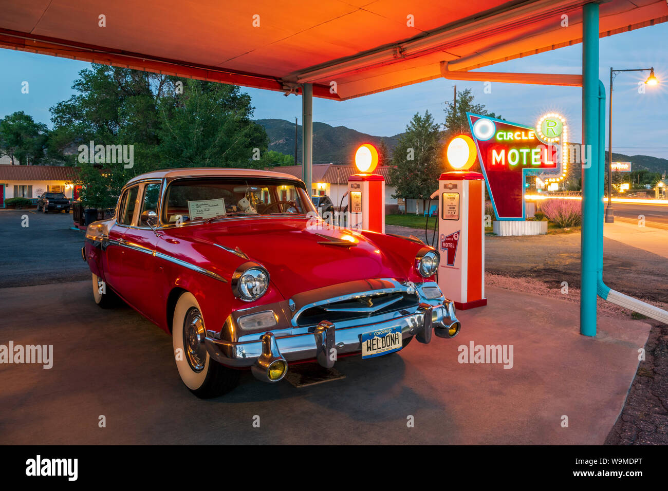 Dämmerung Blick auf 1955 Studebaker President classic car Vor antiken gas Pumpen elektrische Auto Ladegeräte konvertiert geparkt; den Kreis R Motel; Salida Stockfoto