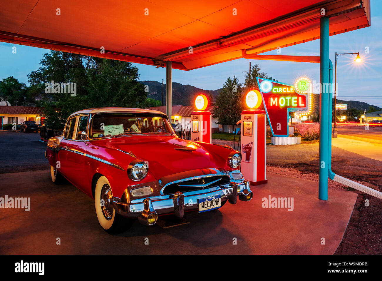 Dämmerung Blick auf 1955 Studebaker President classic car Vor antiken gas Pumpen elektrische Auto Ladegeräte konvertiert geparkt; den Kreis R Motel; Salida Stockfoto