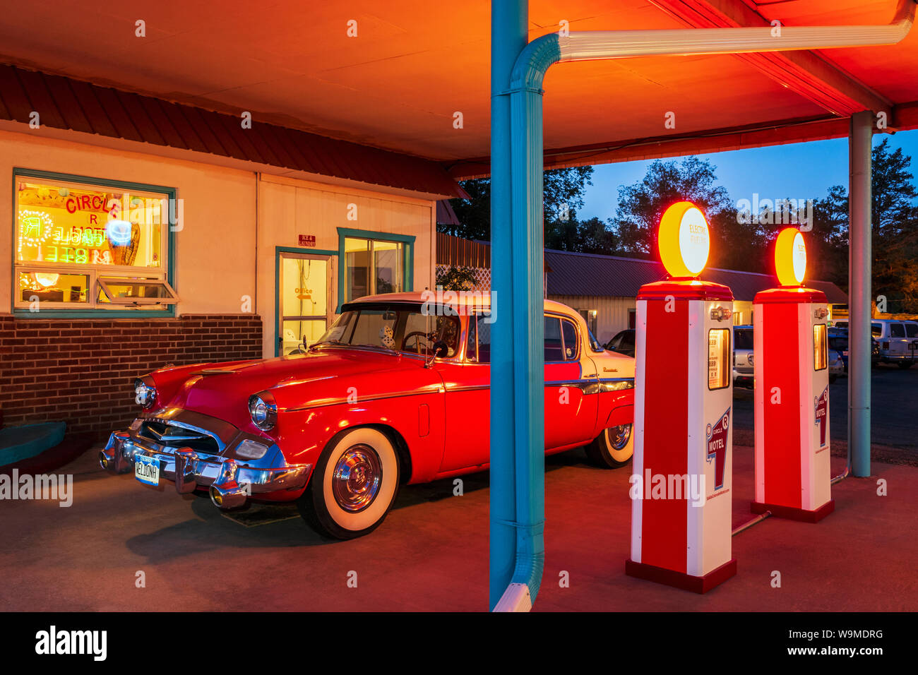 Dämmerung Blick auf 1955 Studebaker President classic car Vor antiken gas Pumpen elektrische Auto Ladegeräte konvertiert geparkt; den Kreis R Motel; Salida Stockfoto