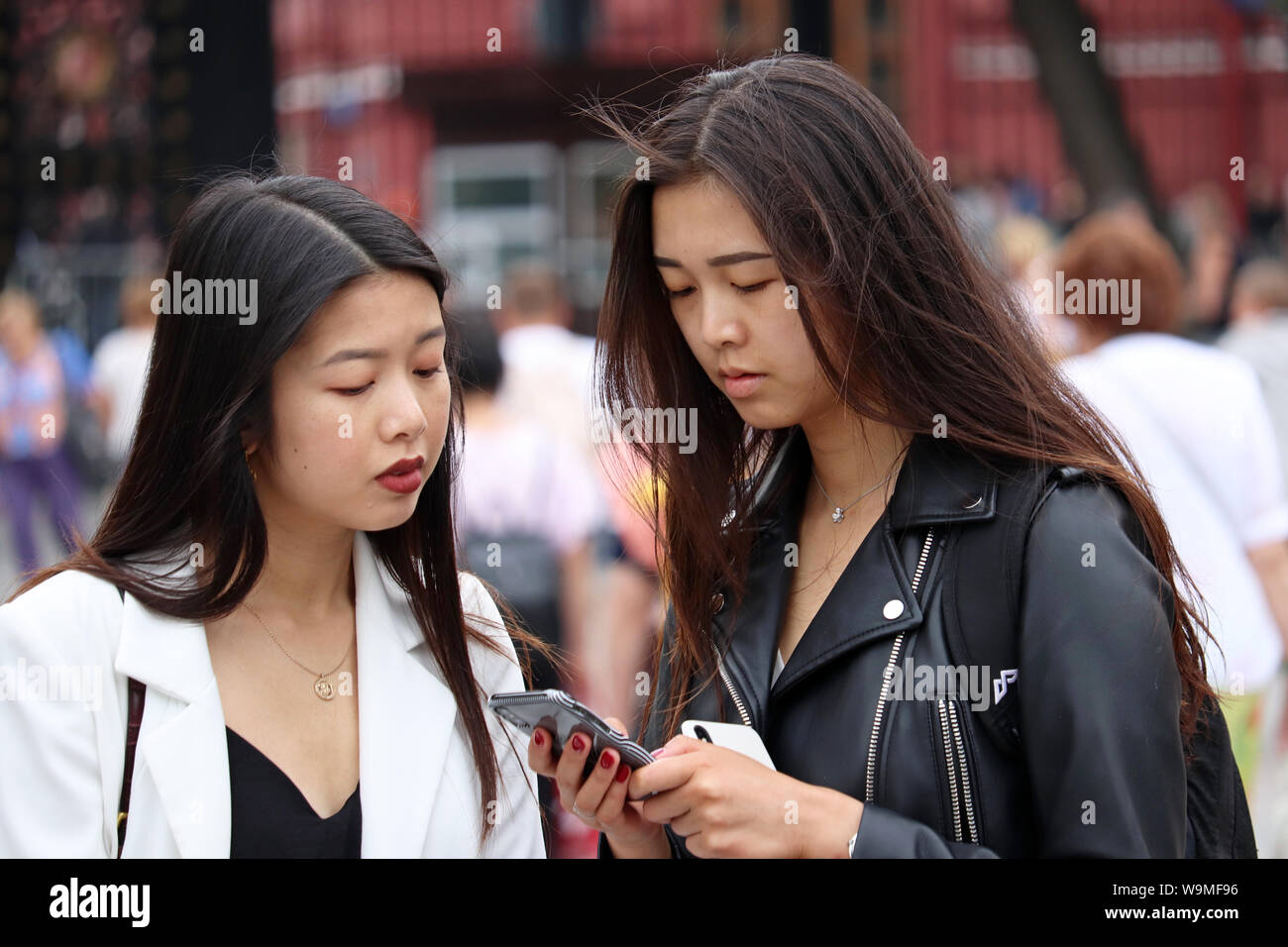 Asiatische Mädchen Blick auf Smartphone steht auf einer Straße der Stadt. Konzept der Online sucht, SMS und mobile Kommunikation Stockfoto