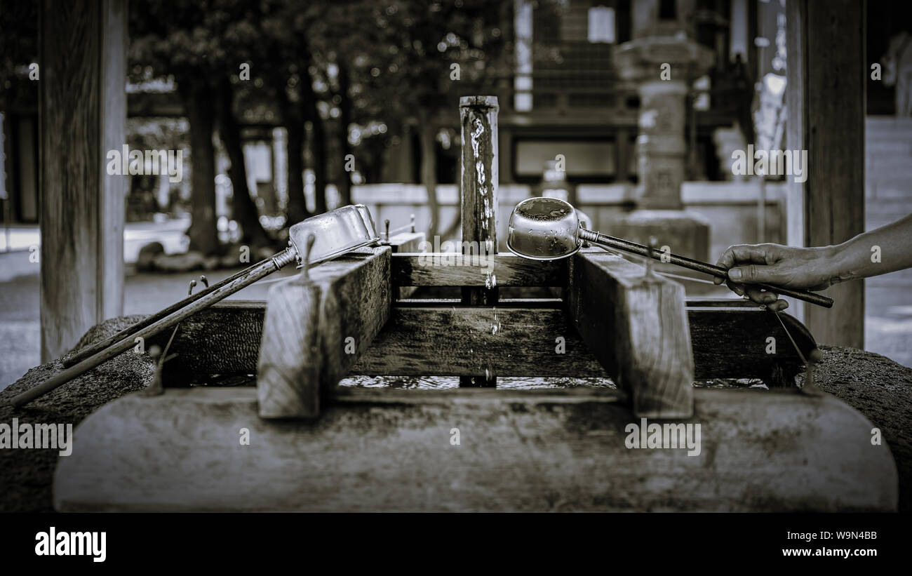 Eine Anbeterin Oberflächen waschen bei der Reinigung Brunnen in der Nähe der Daishi Tempel in Kawasaki, Japan. Stockfoto