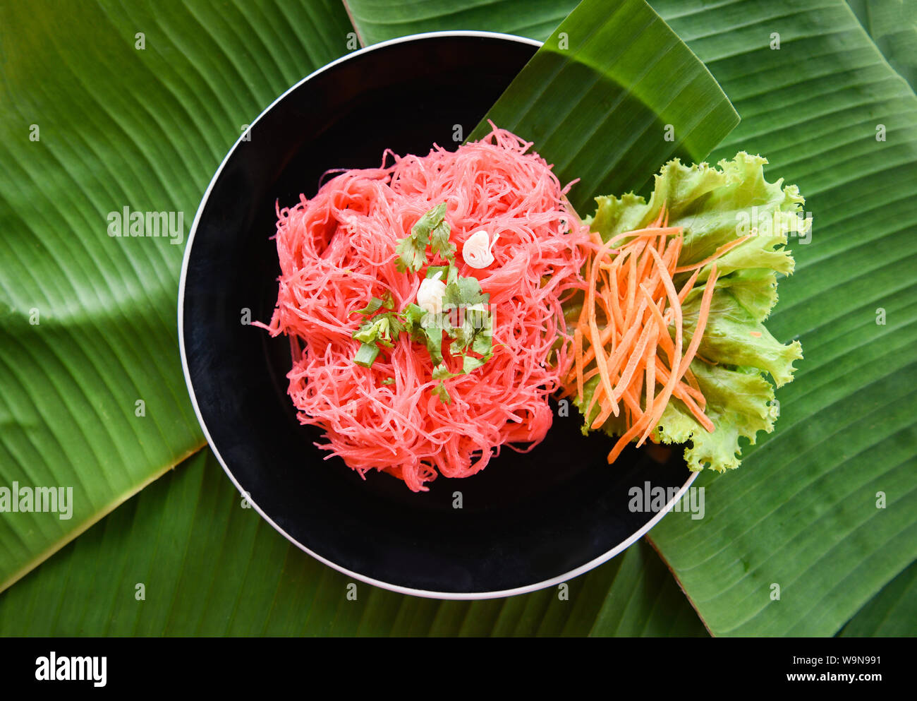 Reis Nudeln rosa Braten und Gemüse-/Rühren gebratener Reis Nudeln mit roter Soße auf dem Teller auf Banane feaf serviert Thai Asiatische Nudeln Stockfoto