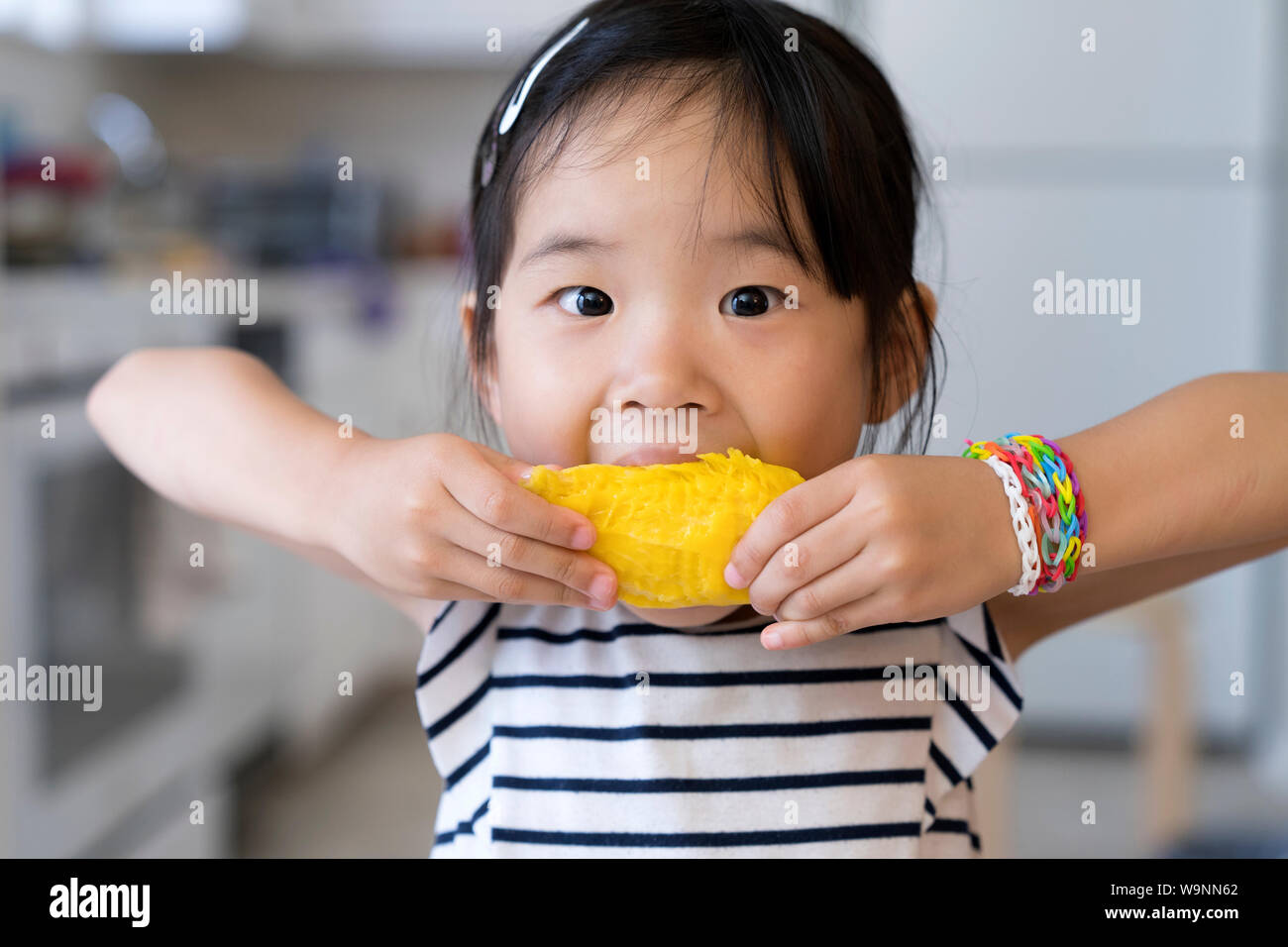 Gerne kleine Mädchen mango Essen Stockfoto