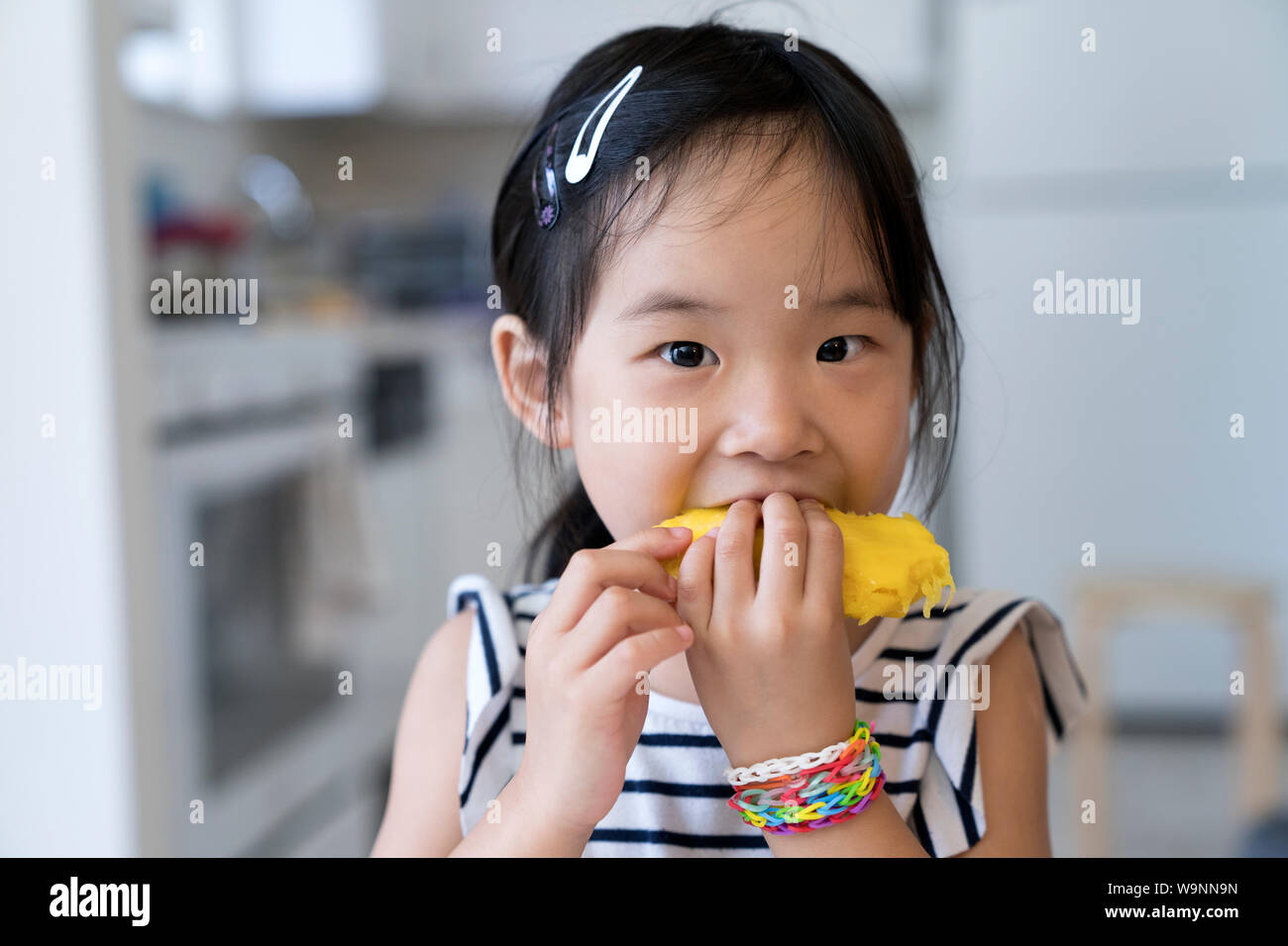 Gerne kleine Mädchen mango Essen Stockfoto