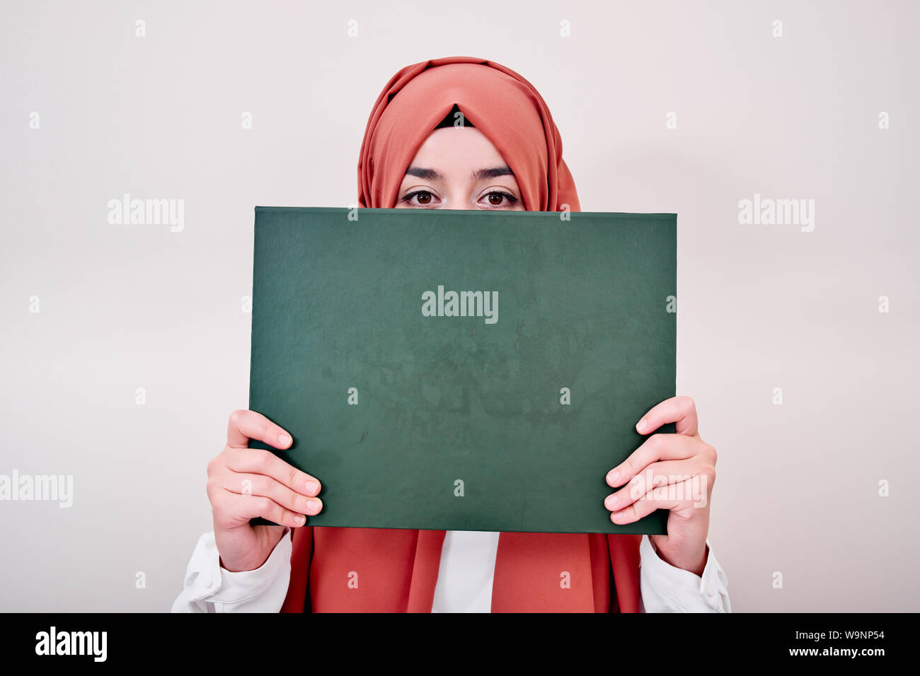 Hijab muslimische Frau mit Leeren leeren Karton oder Papier, ist sie scheu und versteckte ihr Gesicht Stockfoto