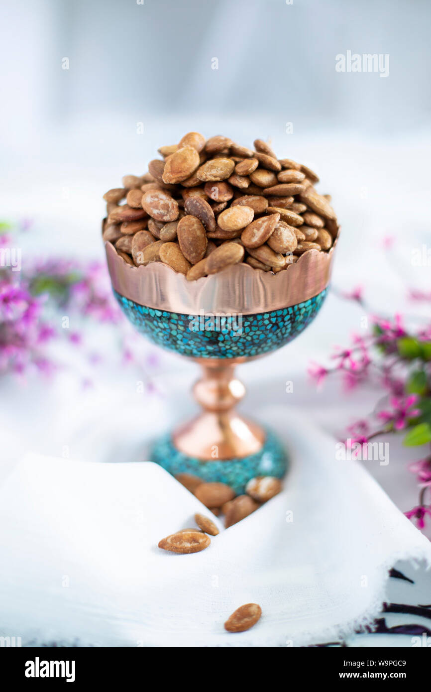 Eine Schüssel mit gerösteten Kürbiskernen in einer traditionellen Türkis- und Kupferschale, garniert mit Blumen Stockfoto
