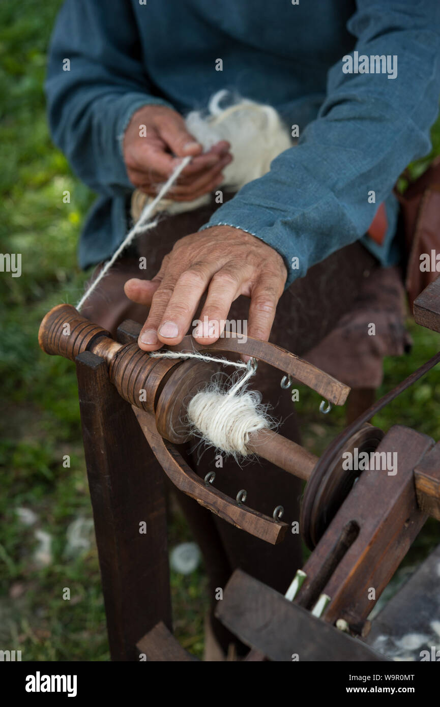 Handwerker mit einem alten Spinnrad wolle in Garn zu drehen. Stockfoto