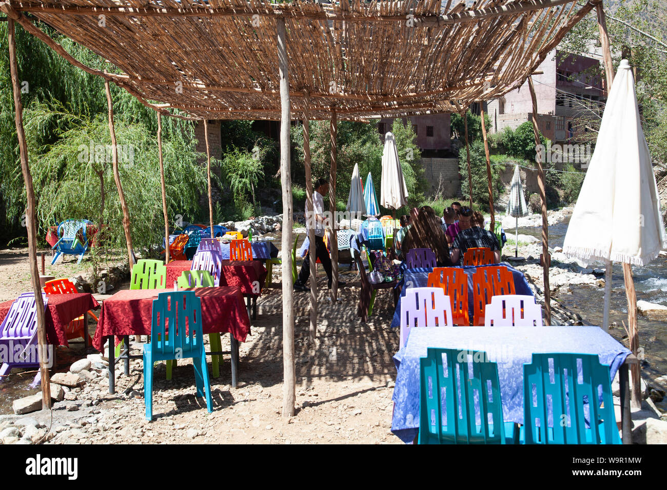 Die Leute sitzen in den Restaurants am Fluss bei Sti Fadma, Ourika Tal in den Atlas, Marokko Stockfoto