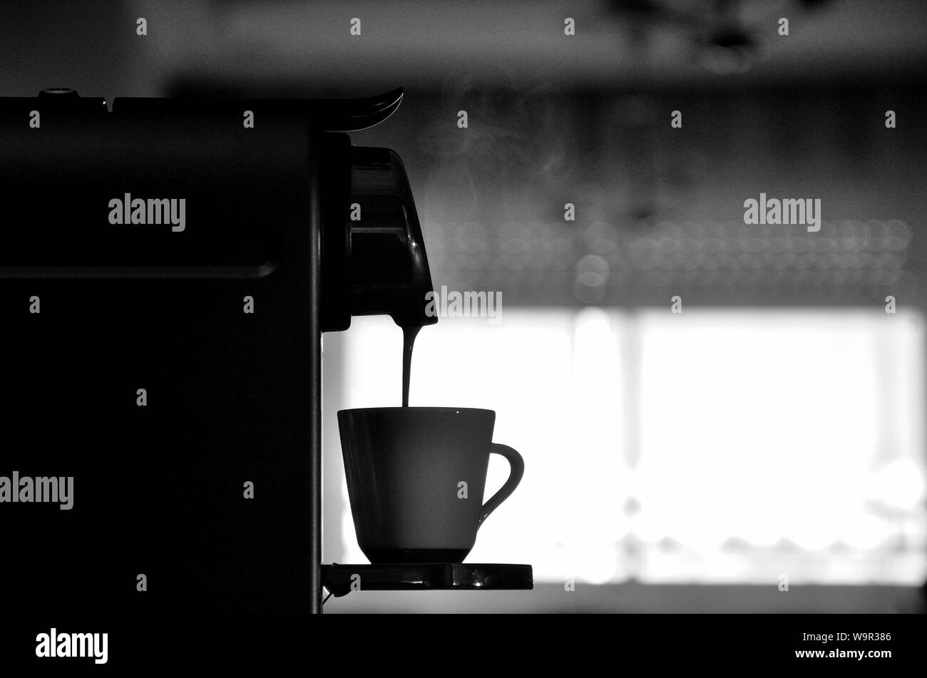 Espressomaschine in Silhouette, füllen Sie eine Tasse Kaffee mit Licht Dampf. Stockfoto