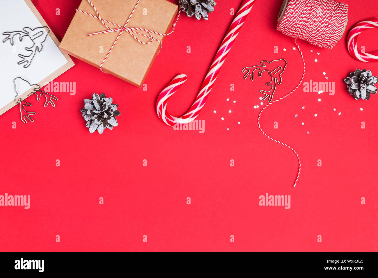 Weihnachten verwandten Objekten auf roten Hintergrund. Flach mit Geschenkbox, candy Kegel und andere kleine Elemente und Platz für Text Stockfoto