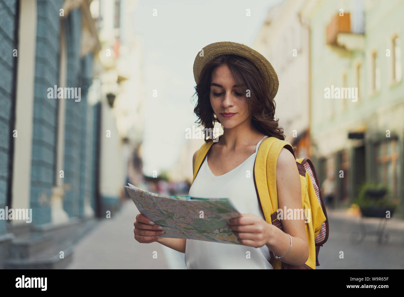 Frau Touristen in die Karte schauen auf die Straße, in der sich europäische Stadt, Reisen in Europa. Mit einem Kurvigen brünette Haare. Einen Rucksack und einen Hut. Stockfoto