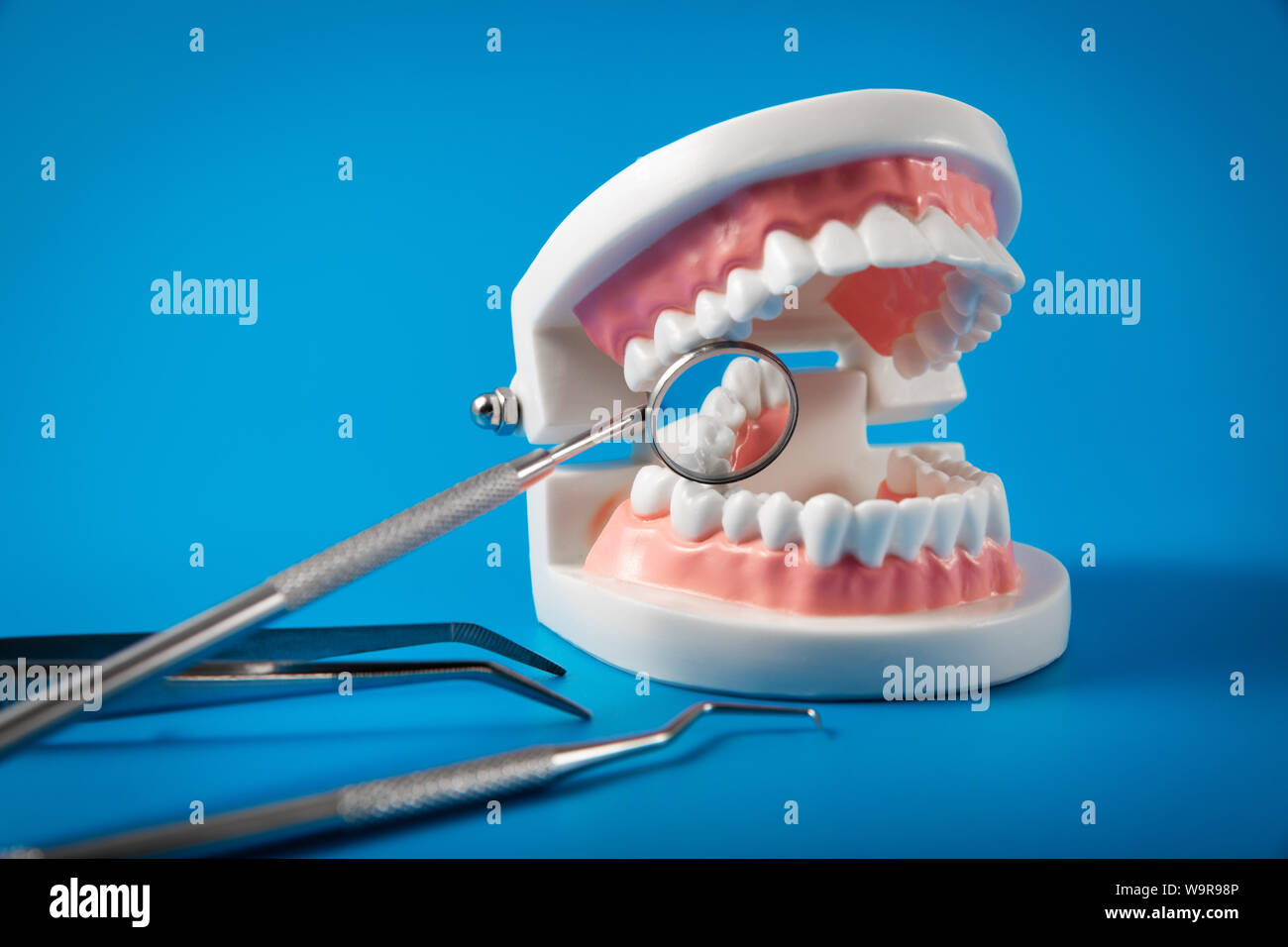 Zahnpflege und Behandlung - Zahn Modell und Zahnarzt Tools auf blauem Hintergrund Stockfoto