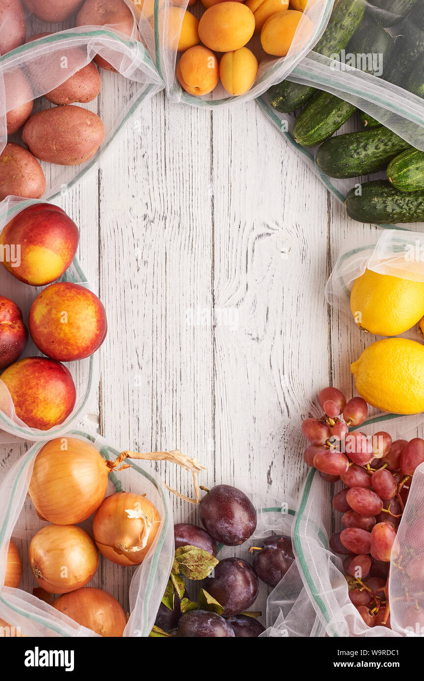 Rahmen von Obst und Gemüse in wiederverwendbare eco Beutel am weißen Holz- Hintergrund. Recycling Taschen anstelle von Plastiktüten. Kunststoff frei. Vertikale. Top vie Stockfoto