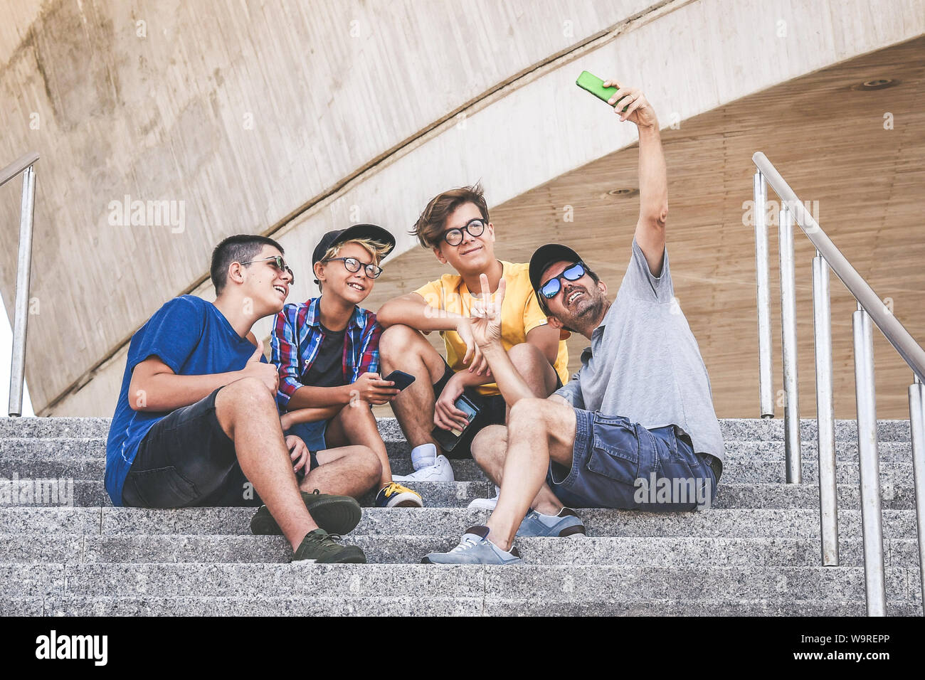 Gruppe von Jugendlichen, die selfie mit Smartphone. Vater und Söhne genießen Urlaub vor Beginn der Schule. Trendy Familie Freigeben von Medien mit Fernbedienung Stockfoto