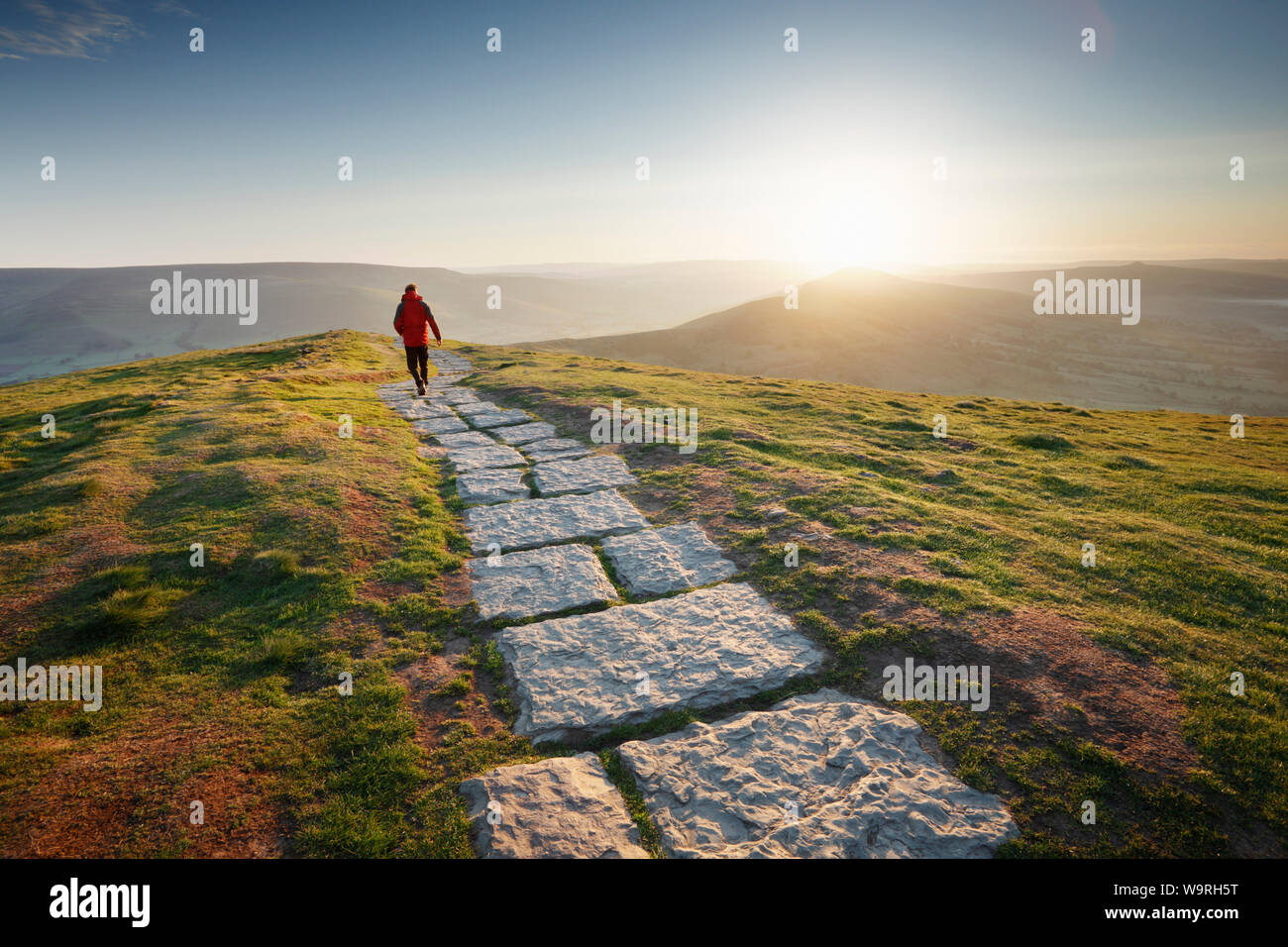Einsamer Wanderer auf dem Fußweg von Mam Tor Hill verlieren. Sunrise. Peak District National Park. Derbyshire. UK. Stockfoto
