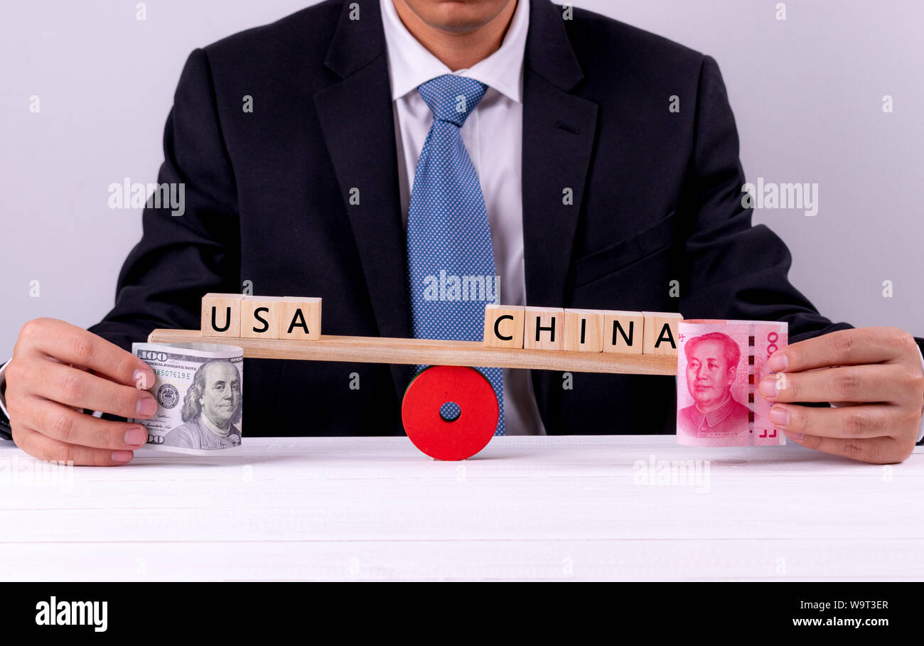 Die Hand des Closeup Geschäftsmann holding Banknote zwischen den USA und China über die Wippe. Handelskrieg, Tarif-, Steuer Barriere zwischen den USA und China. Stockfoto