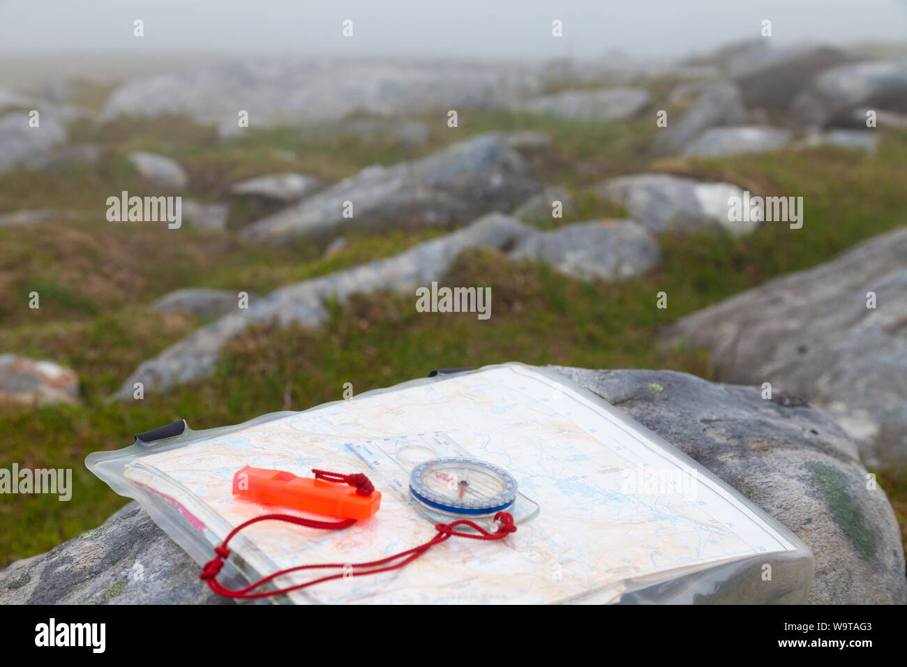 Nahaufnahme von Navigationshilfen Kompass mit Pfeifen und Karte auf einer schottischen Hügel im Nebel. Stockfoto