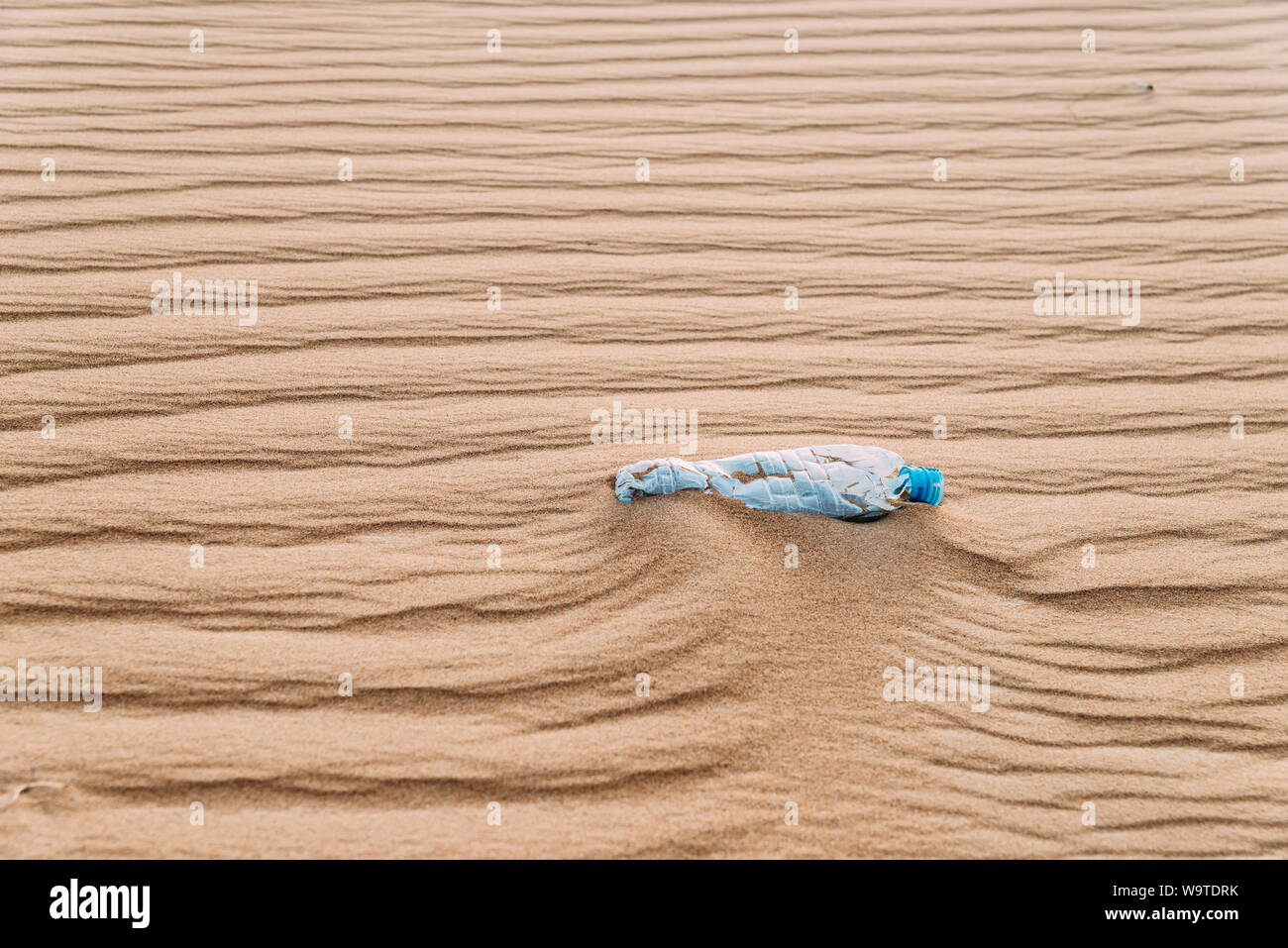 Der verwendete Kunststoff Flasche Wasser sitzen in einer Düne Wüste mit Mustern. Stockfoto