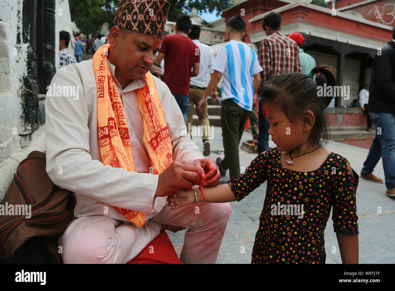 Kathmandu, Nepal. 15 August, 2019. Hindu preist das Binden der Lauffläche für junge Mädchen an Pashupatinath Tempel. Sarita Khadka/Alamy leben Nachrichten Stockfoto