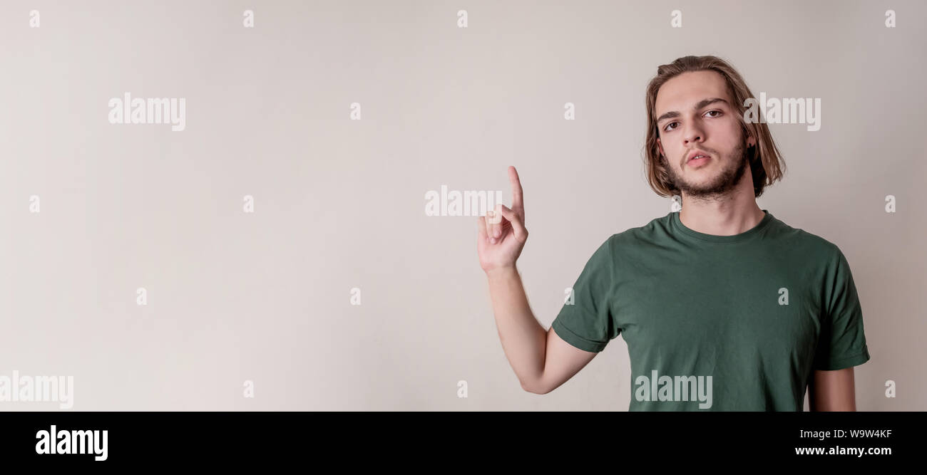 Junger hübscher Kerl oder Mann sein Zeigefinger nach oben an Copyspace leeren Bereich, und isoliert Hintergrund Stockfoto