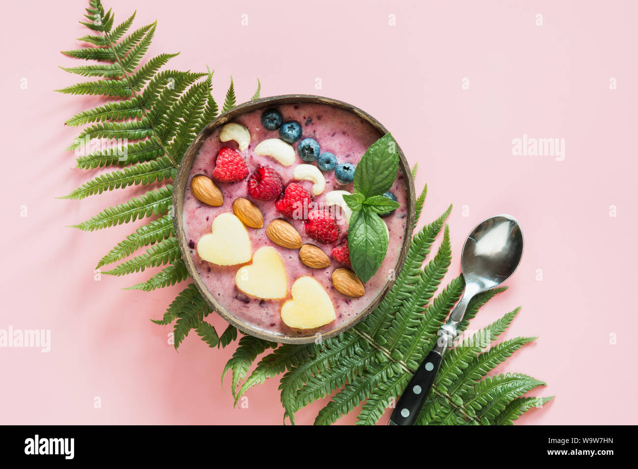 Gesundes Frühstück Banane und blueberry Smoothie mit Früchten in Coconut Schüssel auf rosa Hintergrund eingerichtet. Blick von oben. Sauber Essen, vegetarische fo Stockfoto