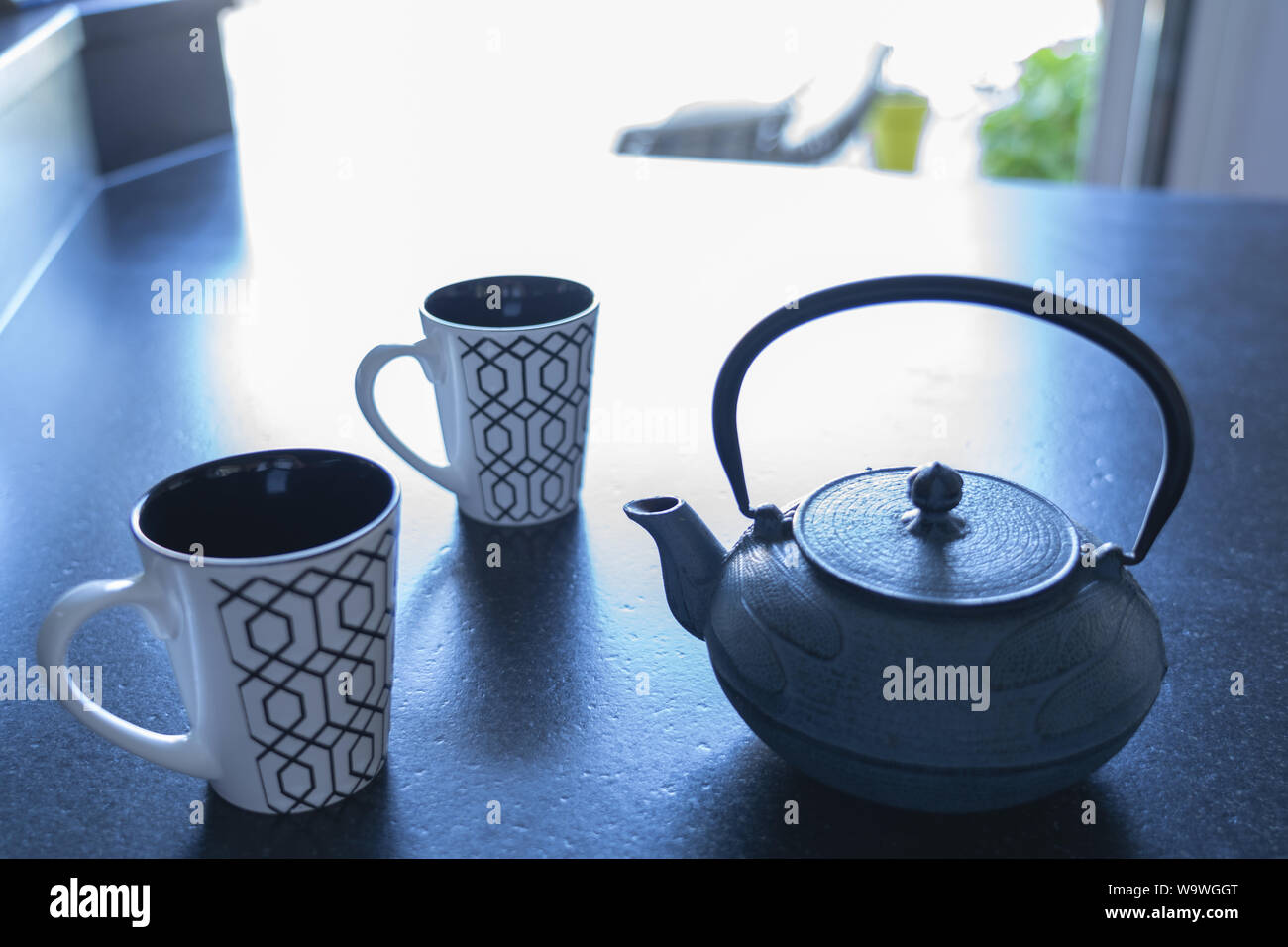 Zwei Tassen und eine gusseiserne Teekanne auf schwarzem Marmor tisch Stockfoto