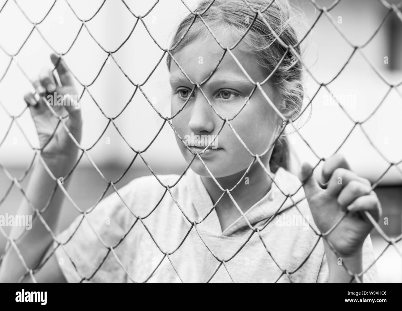 Porträt der jungen kaukasischen Mädchen hinter dem Netz. Soziale Fragen, kid Depression und Traurigkeit. Schwarzweiß gedreht. Stockfoto