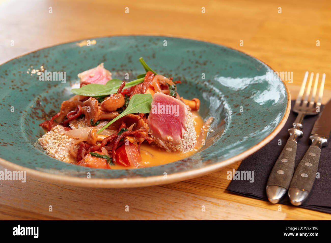 Gegrillter Thunfisch mit Salami und girole Pilze auf Tisch im Restaurant Stockfoto