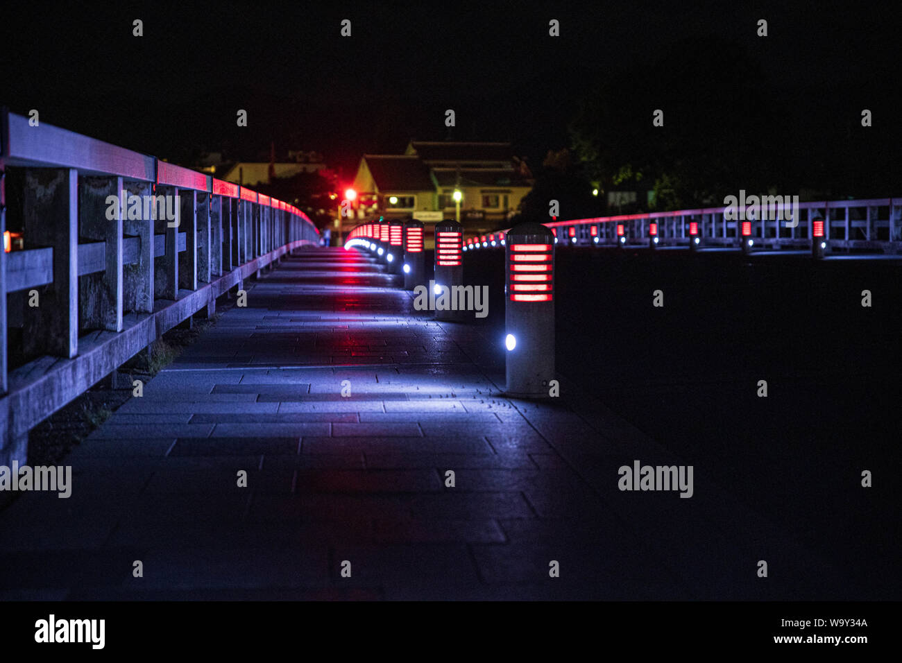 Lichter und Geländer auf dunklen Bridge bei Nacht Stockfoto