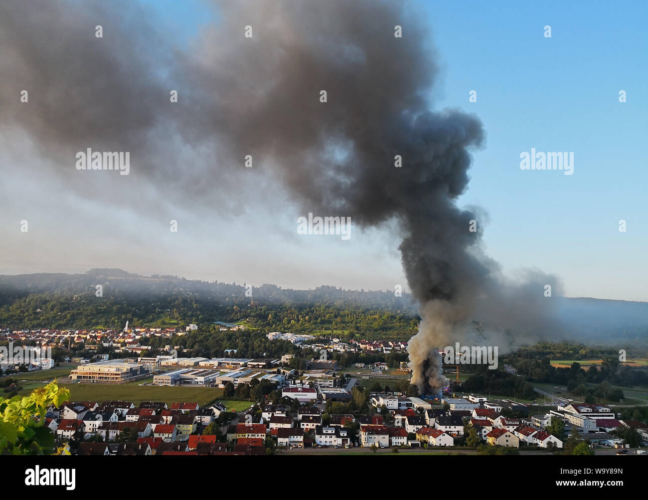 Remshalden, Deutschland. 16 Aug, 2019. Rauch steigt in den Himmel über der Stadt, die im Falle eines Brandes in Remshalden bei Stuttgart. Das Feuer verursacht starke Rauchentwicklung, der dunkle Rauch kann für Meilen gesehen werden. Credit: Andreas Rosar/dpa/Alamy leben Nachrichten Stockfoto