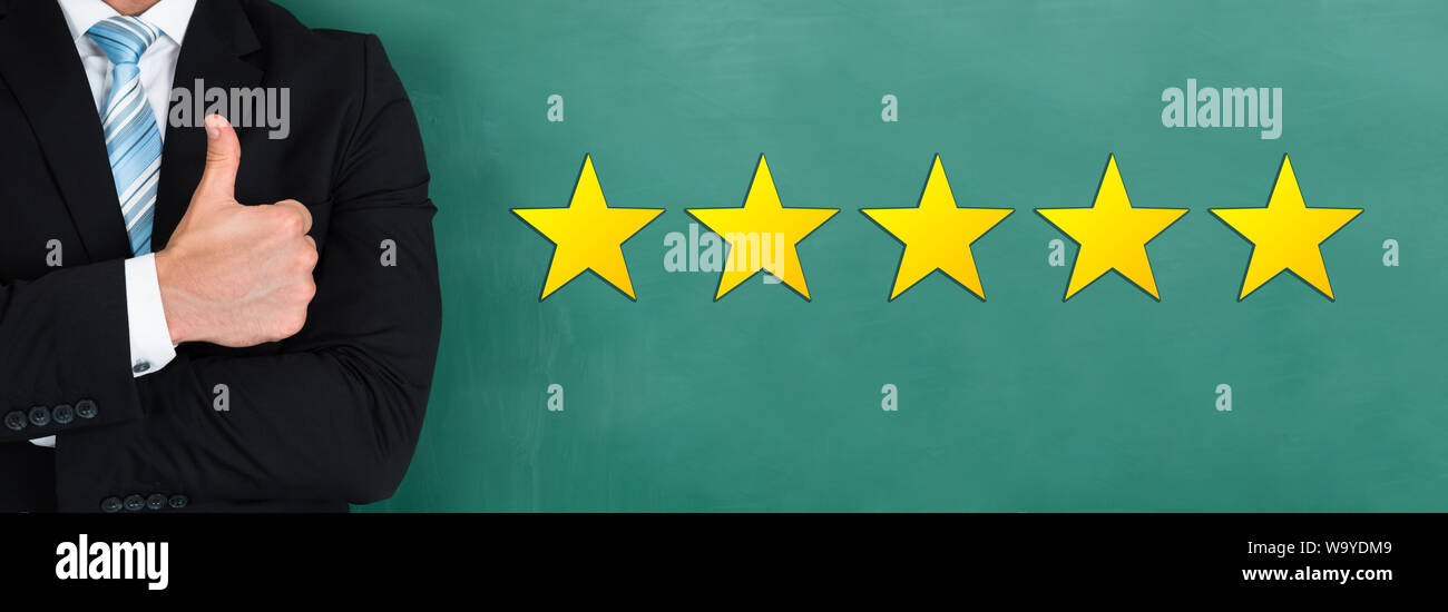Nahaufnahme der Geschäftsmann mit Daumen hoch, mit Gelb fünf Sterne auf grüner Tafel Stockfoto