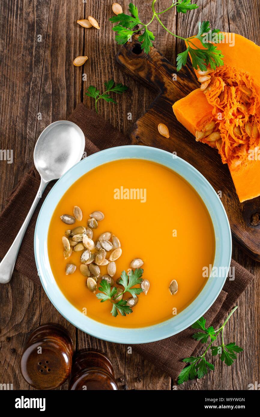 Kürbissuppe. Vegetarische Suppe mit Kürbiskerne in Schale auf Holztisch, Ansicht von oben Stockfoto