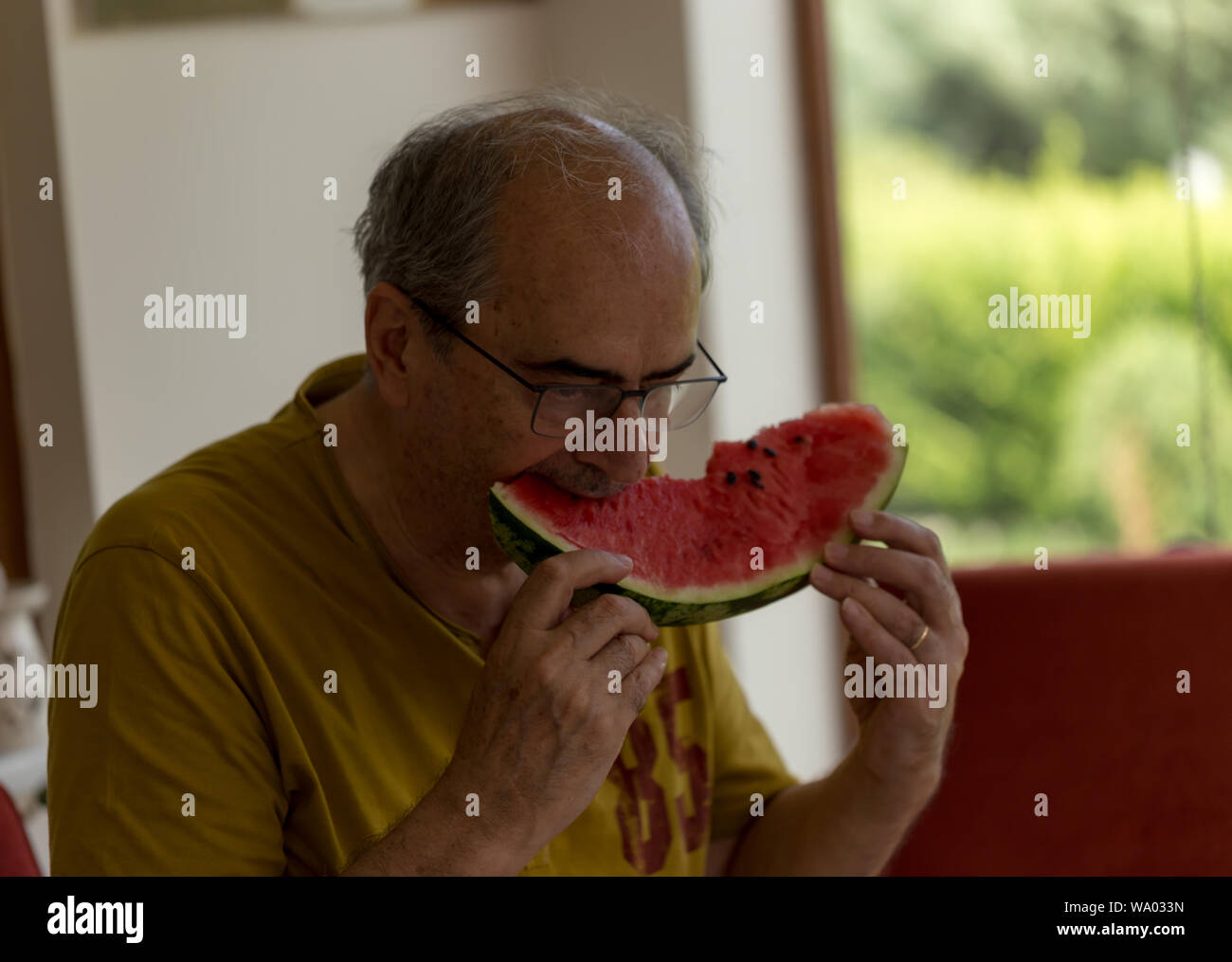 Im mittleren Alter Mann essen ein Stück Wassermelone Stockfoto
