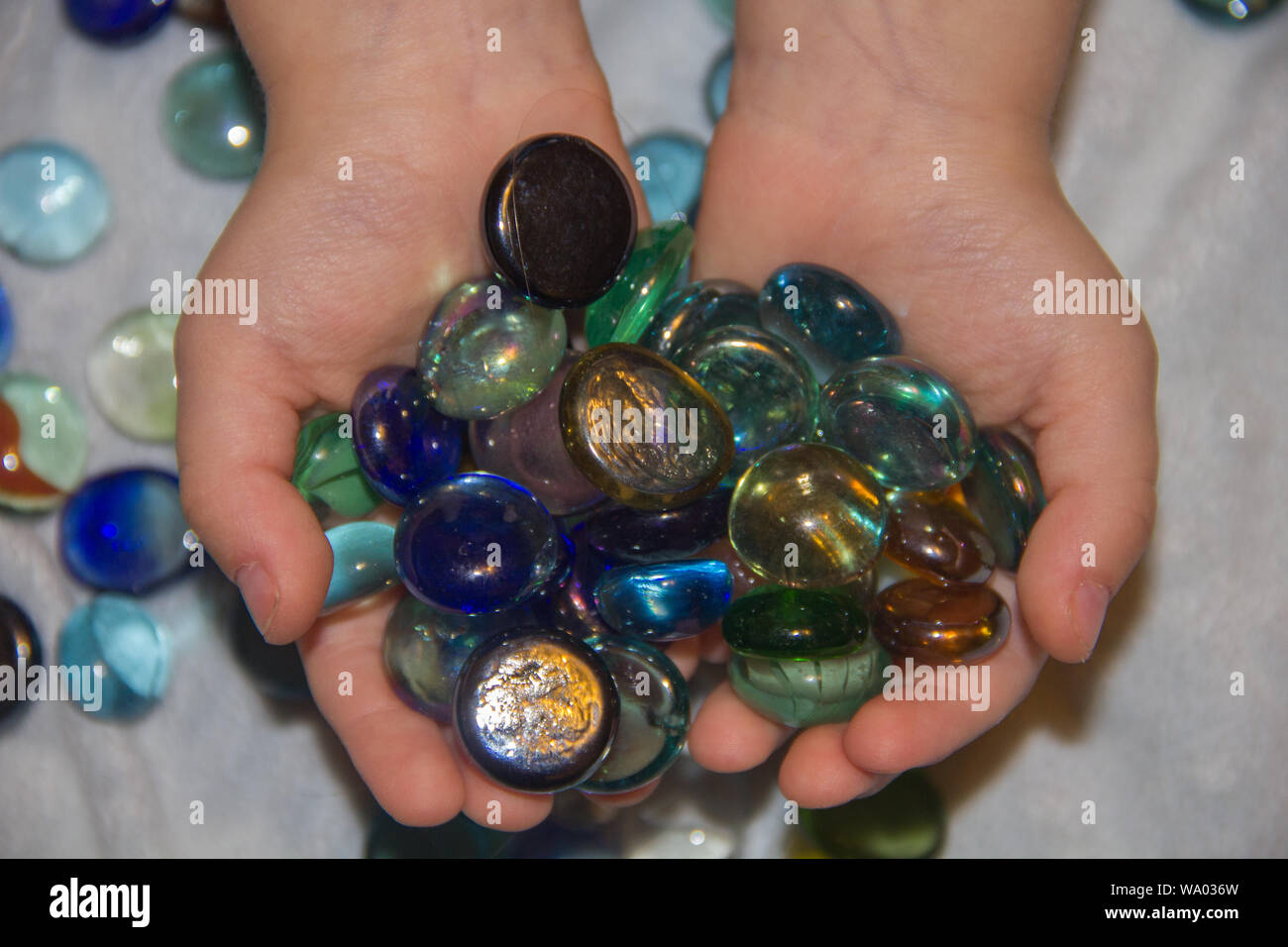 Buntes Glas Kieselsteinen. Farbige Kugeln aus Glas im childs Hand und sensorische Erfahrung Stockfoto