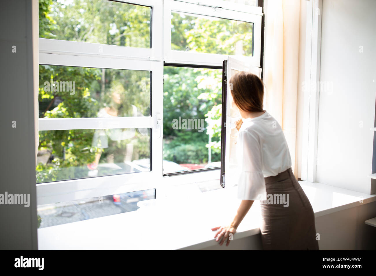 Seitenansicht einer Geschäftsfrau, die durch ein Fenster von einem Bürogebäude Stockfoto