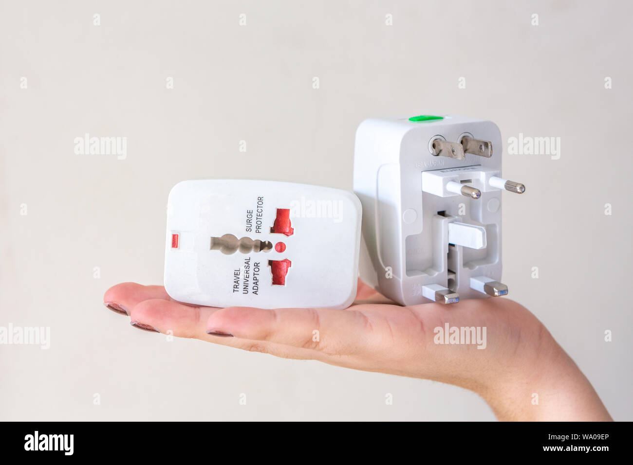Nahaufnahme von Frau Hand universal Steckdose stecker adapter, auf weißem Hintergrund. Zur Verbindung von elektrischen Steckdosen weltweit. Co Stockfoto