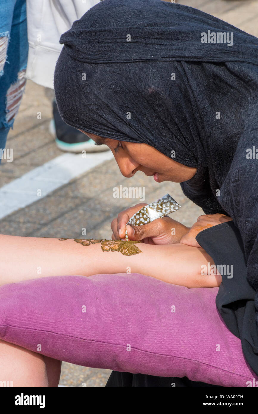 Eine indische oder muslimischen Asiatischen Tätowierer ein Henna Tattoo auf und Arm trägt eine Kapuze. Stockfoto
