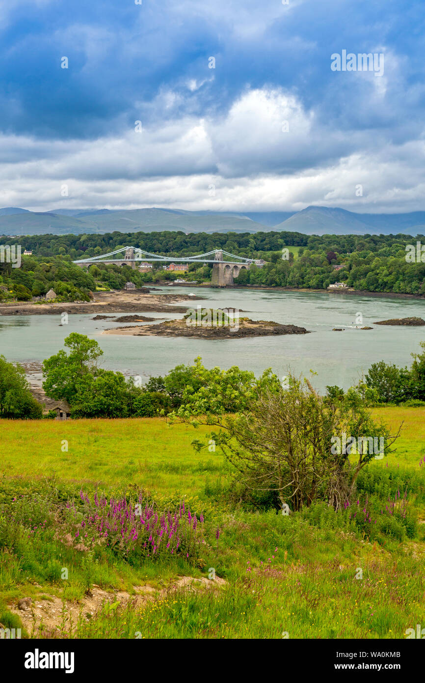 Die historische 1826 Menai Bridge von Thomas Telford nimmt die 5 Straße über die Menai Straits in Anglesey, mit den Bergen von Snowdonia jenseits, Wales, Großbritannien Stockfoto