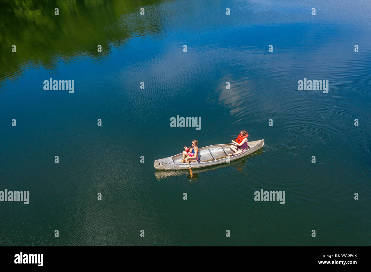 Prairieville, Michigan - zwei Frauen mit einem kleinen Kind paddeln in einem Kanu auf der Stewart See. Stockfoto