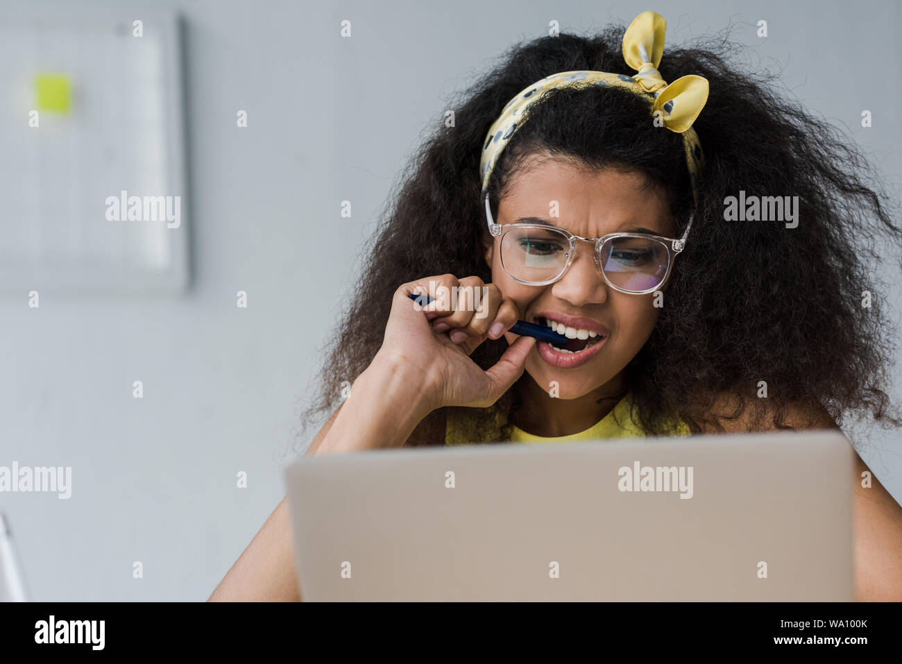 Selektiver Fokus der emotionalen African American Girl beißen Pen bei Laptop suchen Stockfoto