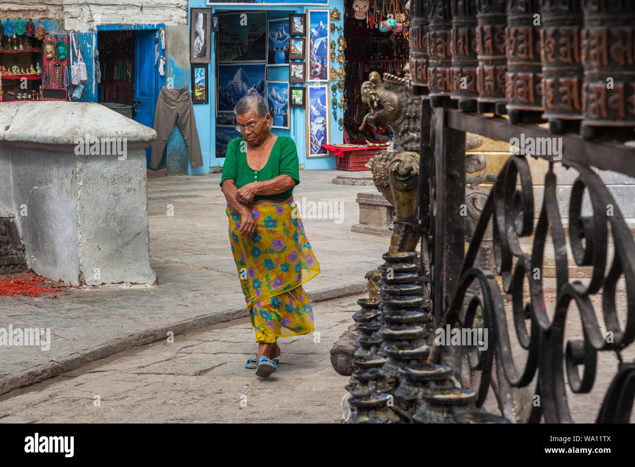 Eine alte Frau bei einem Spaziergang vorbei an gebetsmühlen an Swaymbhunath, Kathmandu, Nepal. Stockfoto