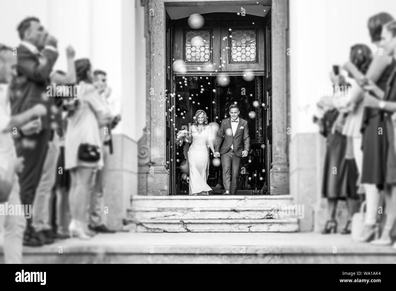 Brautpaar Verlassen der Kirche nach der Trauung, Familie und Freunde feiern ihre Liebe mit der Dusche der Seifenblasen, benutzerdefinierte untergraben. Stockfoto