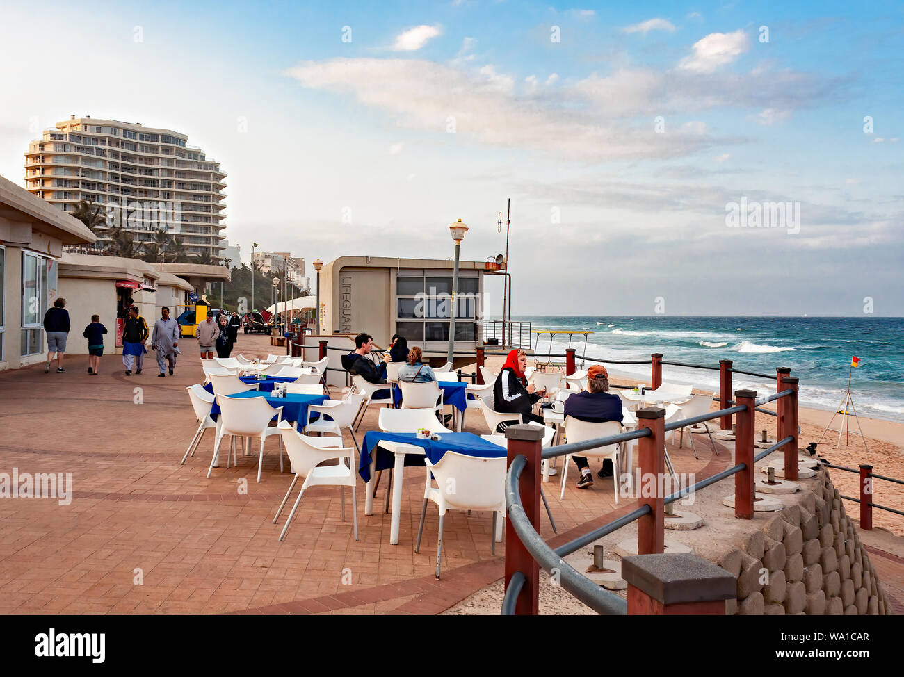 DURBAN, Südafrika - 12. AUGUST 2019: Touristen, Mittagessen in einem Restaurant an der Promenade am Strand in Umhlanga Rocks, in der Nähe von Durban, KwaZulu - Stockfoto