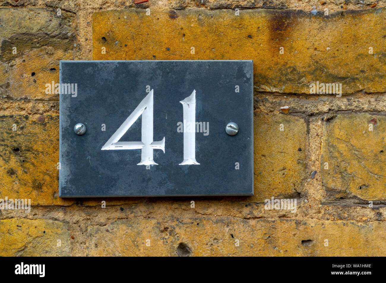 Haus Nummer 41 auf schwarzem Schiefer auf einem gelben Wand Stockfoto