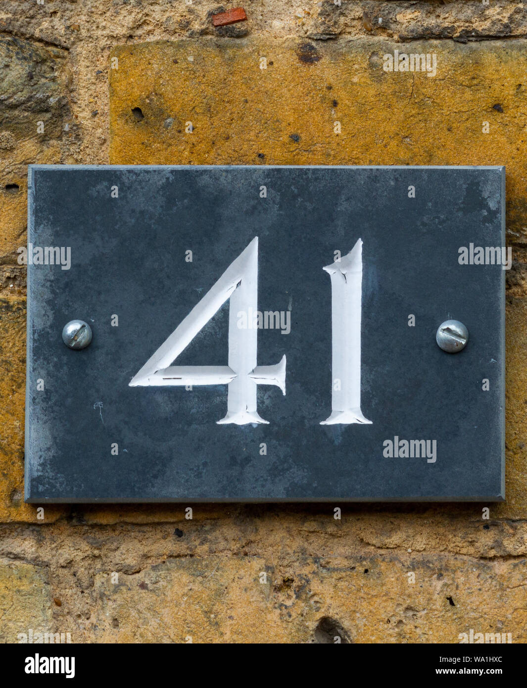 Haus Nummer 41 auf schwarzem Schiefer auf einem gelben Wand Stockfoto