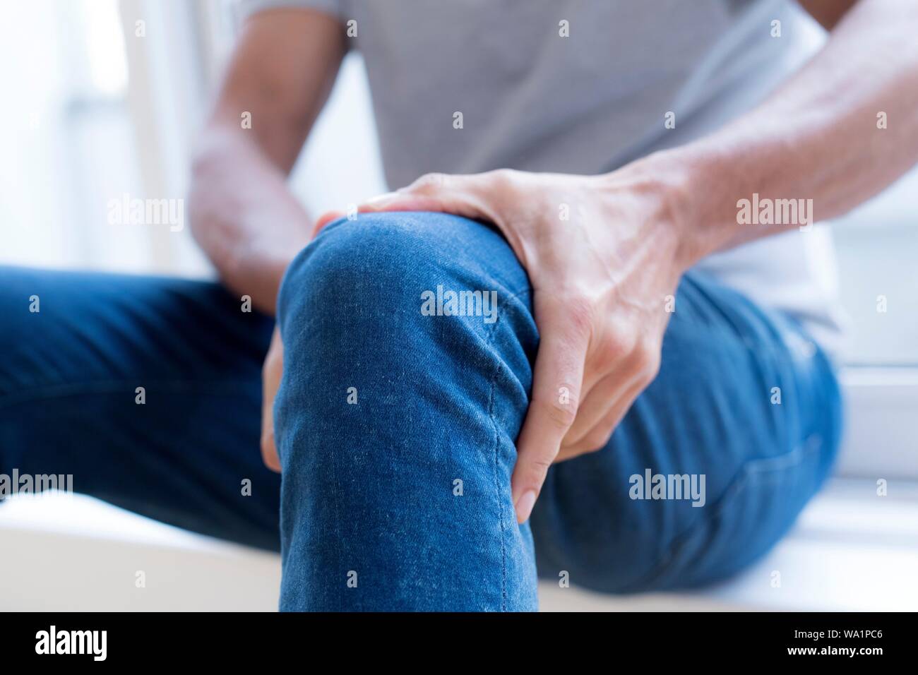 Der Mensch seinem linken Knie Holding in den Schmerz. Stockfoto