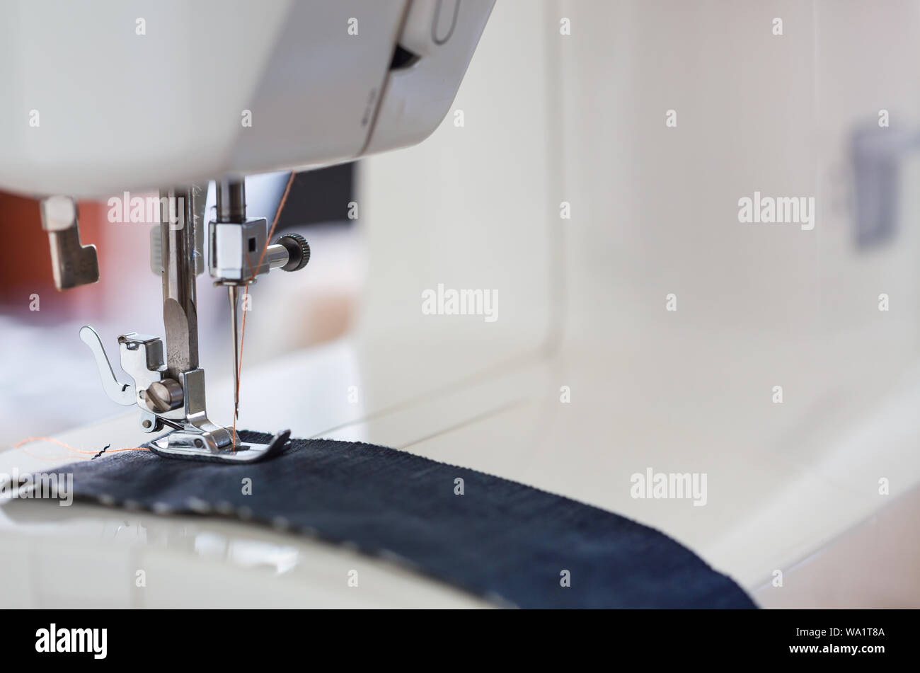 Nähmaschine mit Farbe Faden und Nadel auf eine Tabelle mit unscharfen Hintergrund, Schneider's Arbeit Tabelle, Textil oder feinem Tuch, industrielle Struktur, Stockfoto