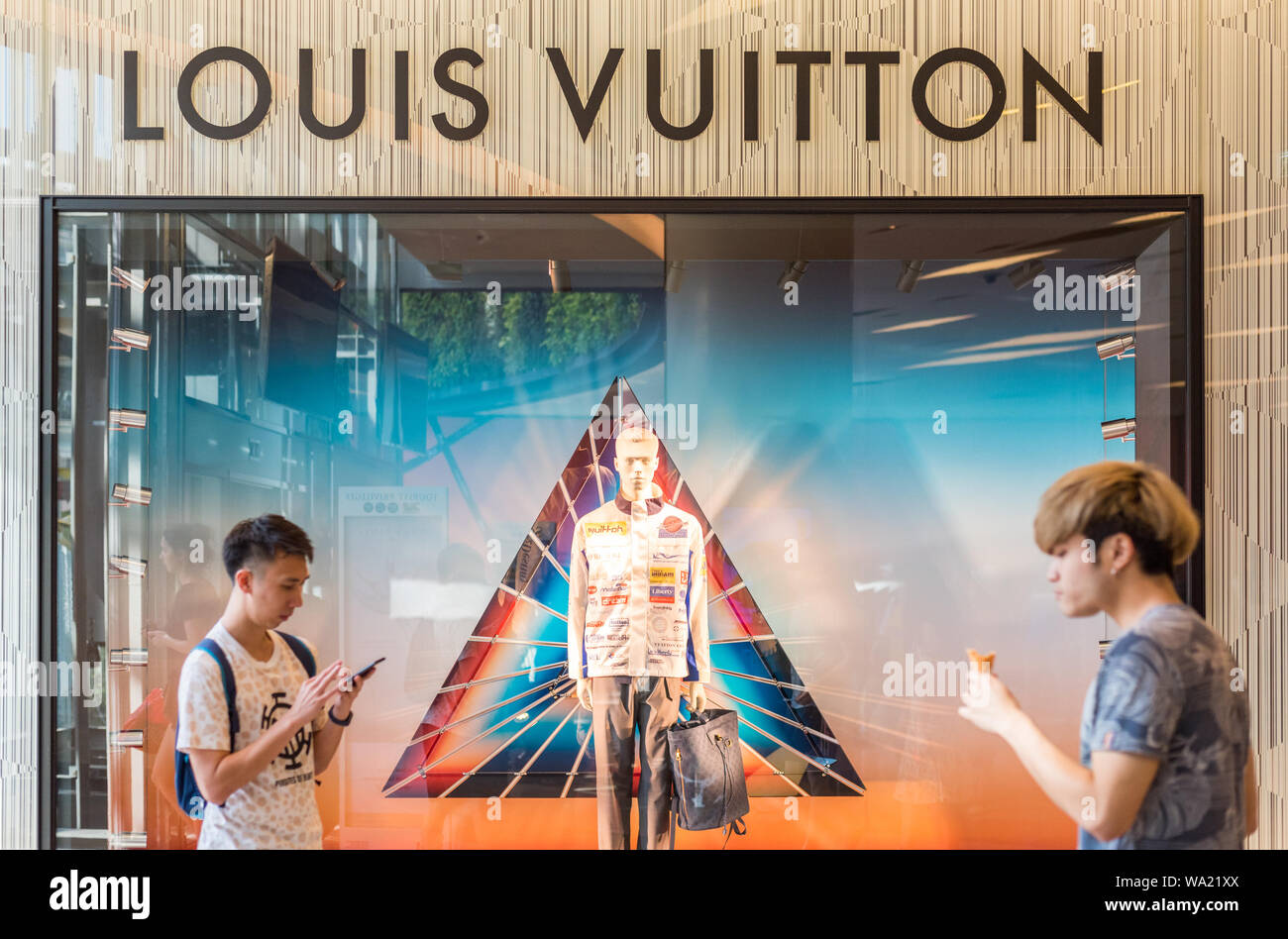 Bangkok, Thailand - 19. Mai 2019: ein Louis Vuitton Fenster Anzeige an einen Shop mit zwei Passanten in Siam Paragon Shopping Mall. Stockfoto