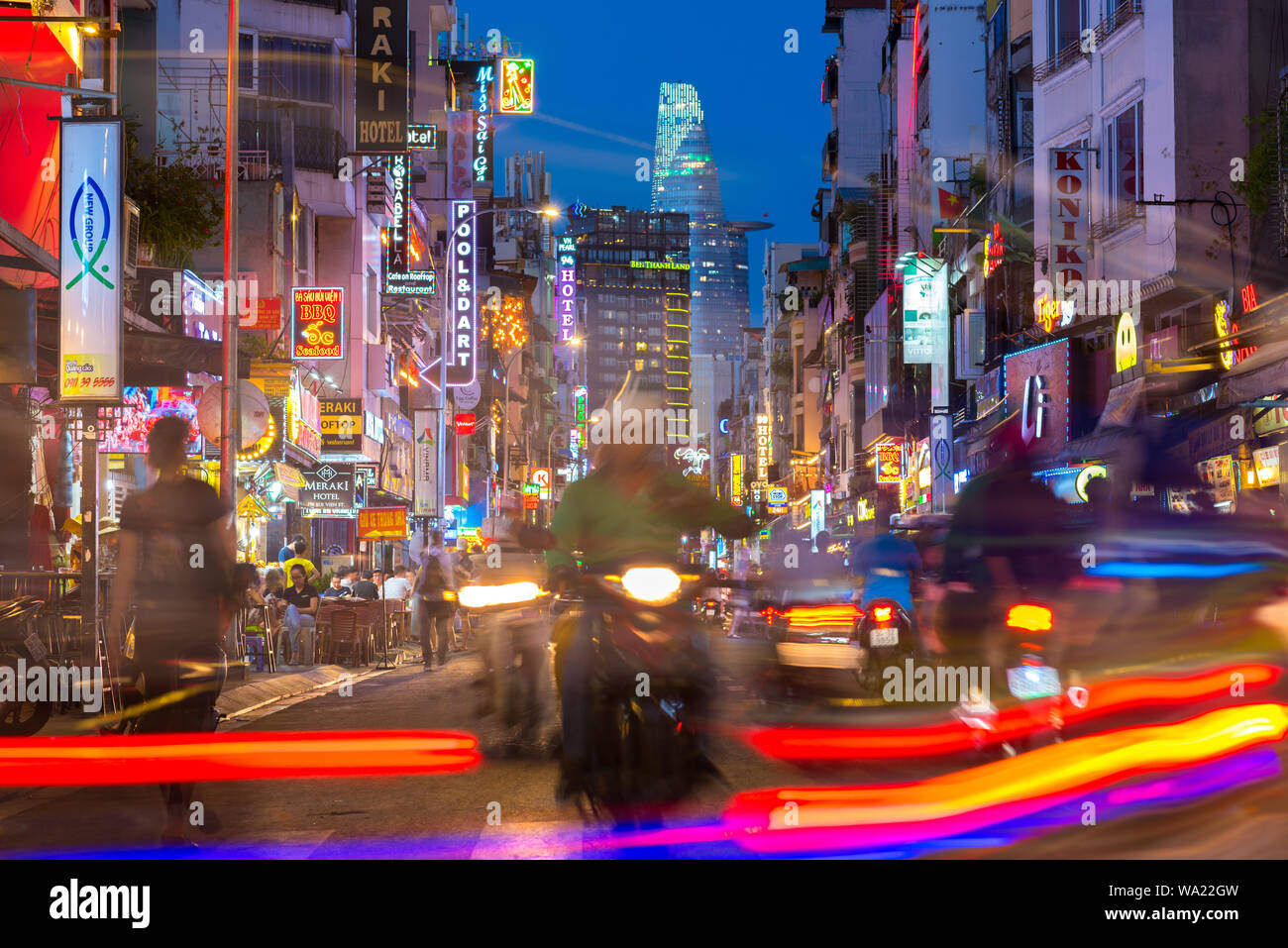Ho Chi Minh City, Vietnam: Bui Vien Straße bei Nacht mit seinen Leuchtreklamen, Silhouetten, Streifen und Bitexco Turm im Hintergrund. Lange Belichtung. Stockfoto